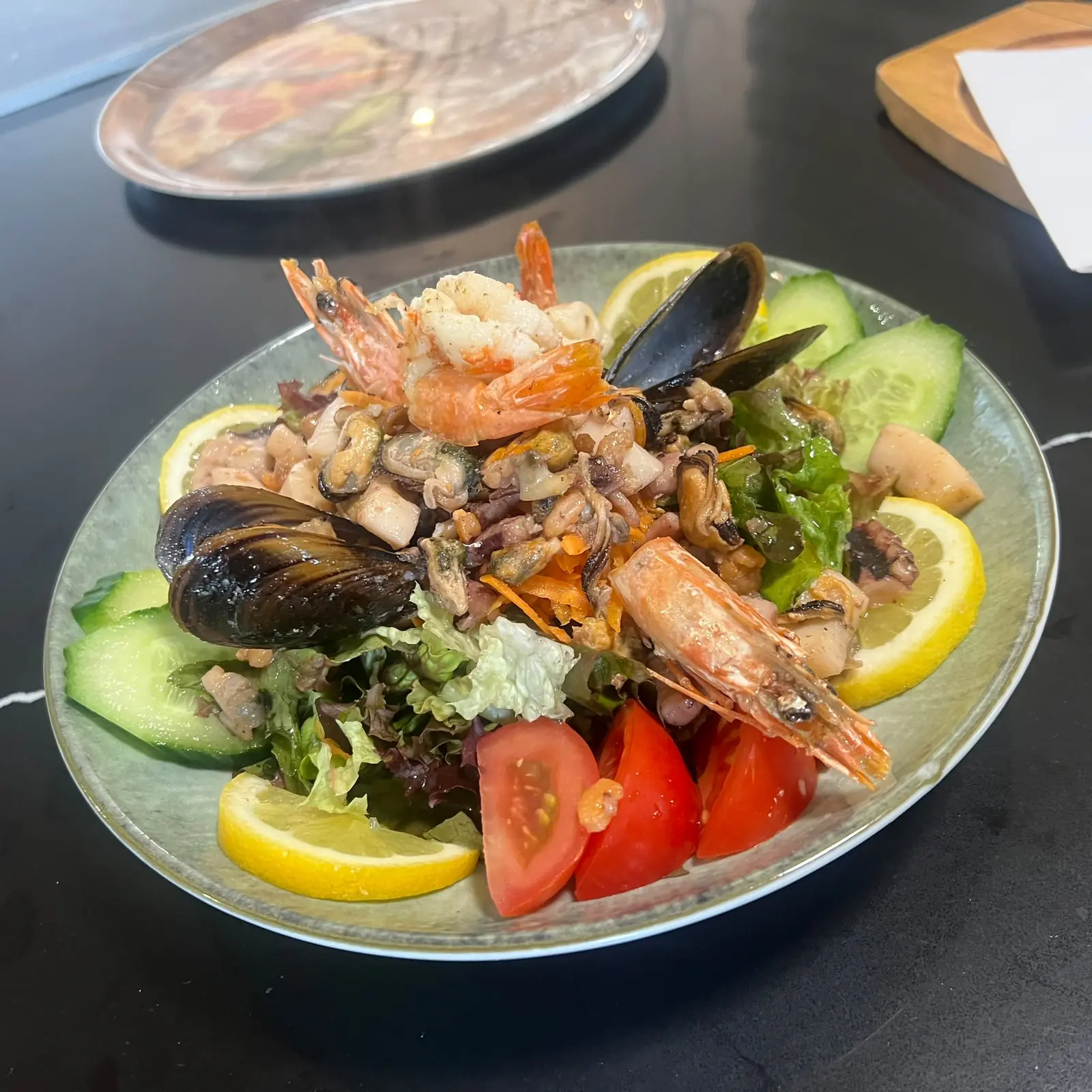 Frischer Meeresfrüchtesalat mit Garnelen, Muscheln, Tintenfisch, Gurken, Tomaten und Zitronenscheiben